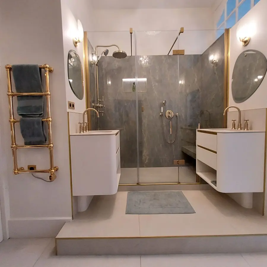 Salle de bain symétrique avec double vasque en dos à dos, douche en décor onyx centrale, robinetterie classique finition dorée