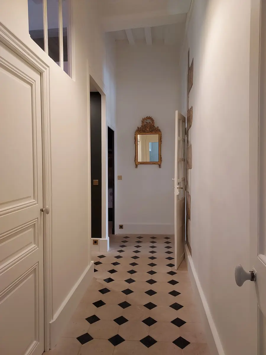 Couloir ancien rénové, carrelage en pierre naturelle à losanges noirs, miroir doré ancien