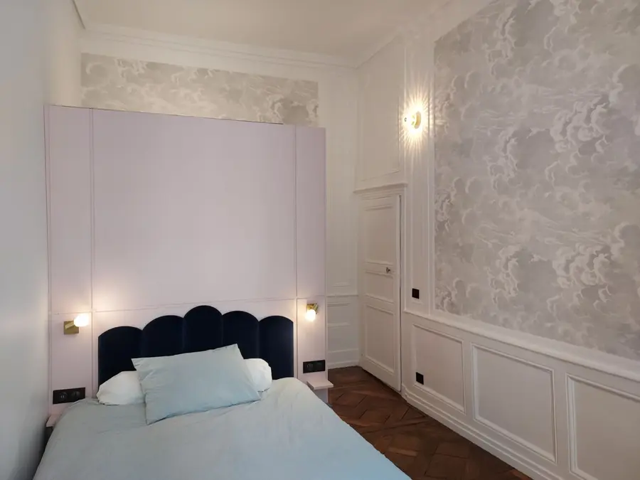 Chambre belle hauteur sous plafond, tête de lit velours bleu marine au dos du dressing ouvert, moulures anciennes préservées