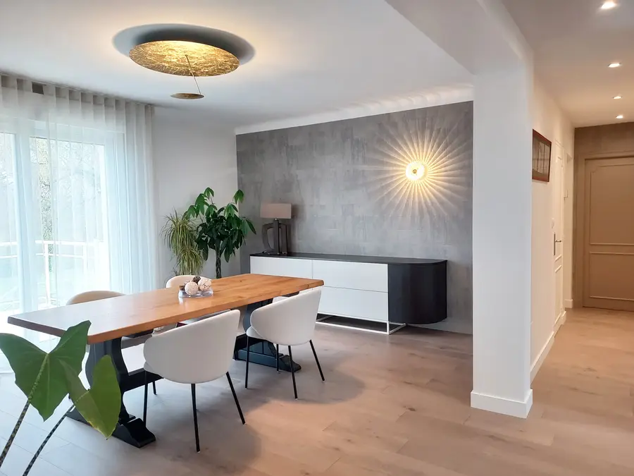 Salle à manger spacieuse, buffet arrondi, luminaire doré, ouverture élargie vers la cuisine